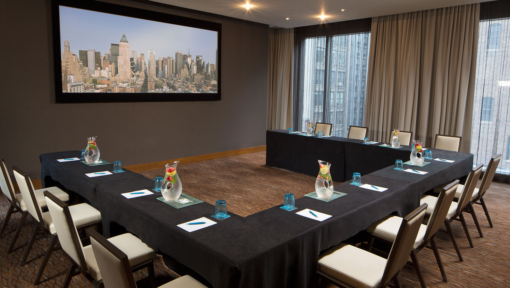 Screening room meeting with u-shape table set up facing towards large presenter screen